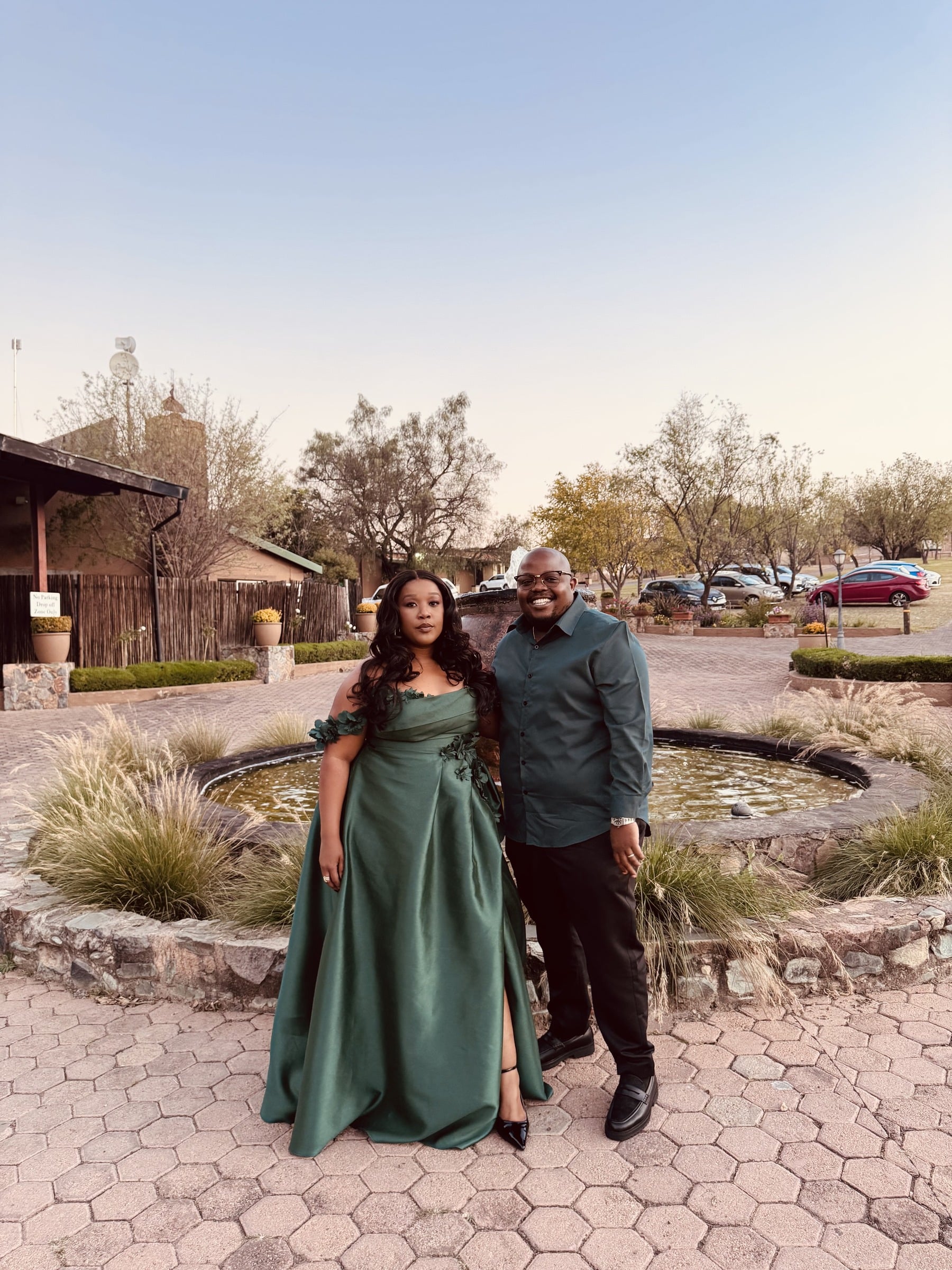 The couple in formal green outfits photographed at a venue