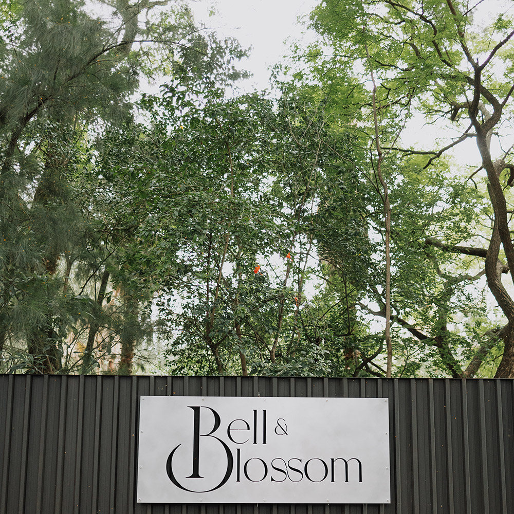 Bell and Blossom venue sign set against tall green trees