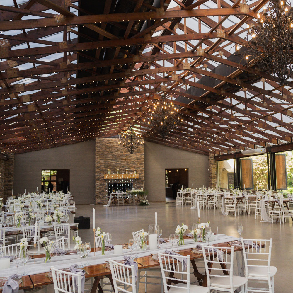Wide interior of the Bell Reception Hall with exposed timber trusses, chandeliers and dressed tables
