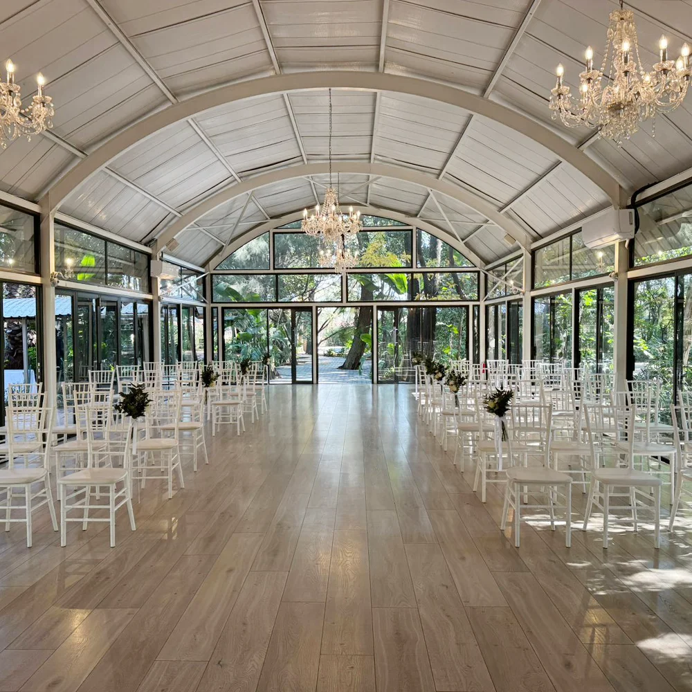 Symmetrical aisle inside the Glass Dome Chapel with white chairs, glass walls and crystal chandeliers