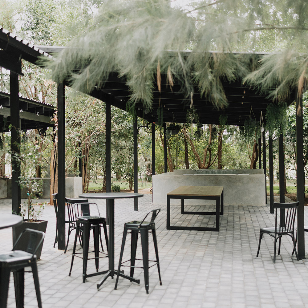 Covered outdoor bar area with black framing, hanging greenery and garden seating